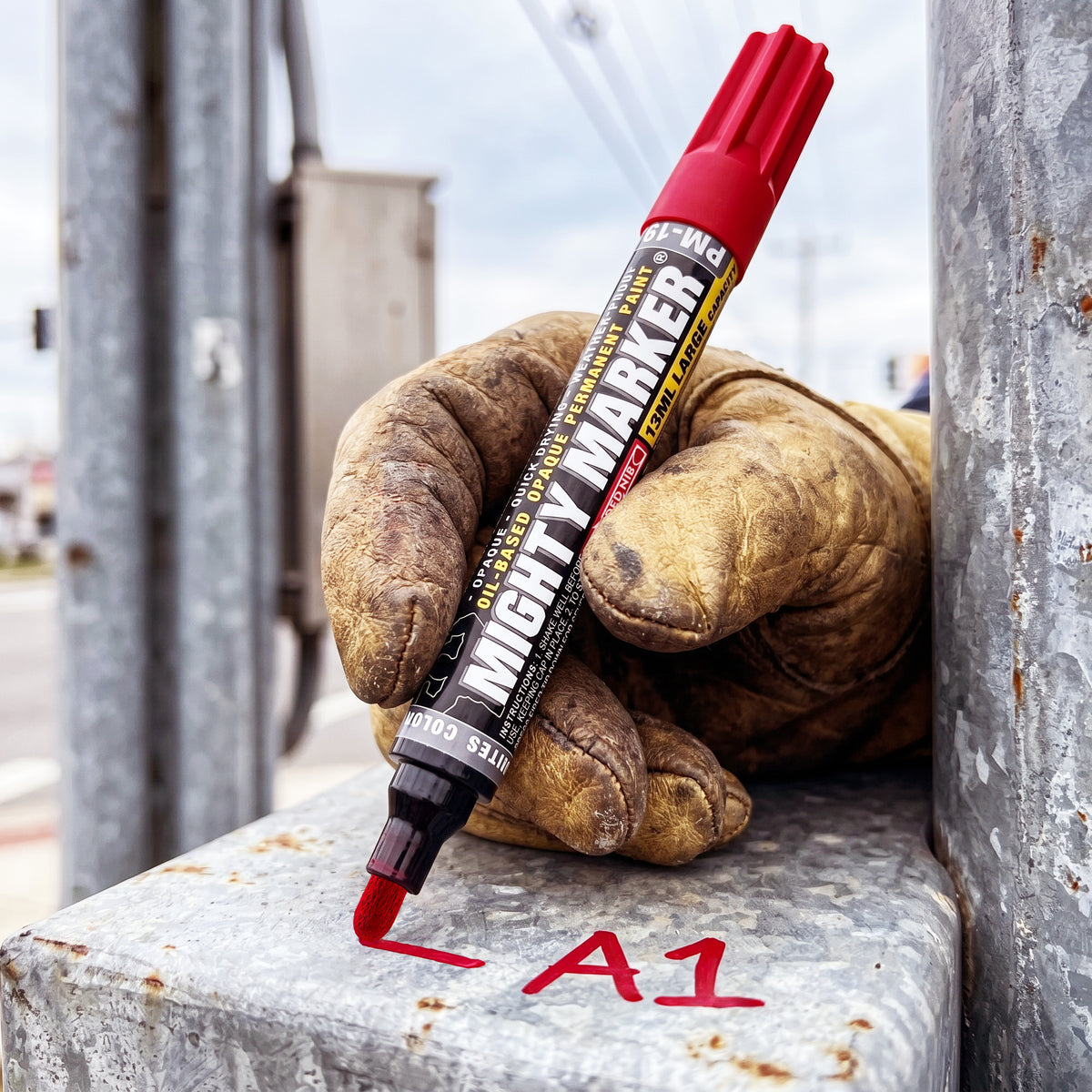 PM-19 Red marker labeled 'Mighty Marker' on a pair of work gloves with 'A1' written on a metal surface.